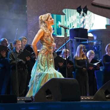 Eine blonde Frau in einem schönen Kleid bei einem Konzert mit einem klassischen Orchester.