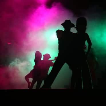 Die Schatten tanzender Paare bei einem Musical, welches effektvoll mit Lichttechnik inszeniert ist.