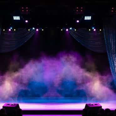 Eine leere Theaterbühne mit Nebel und farbigem Licht.