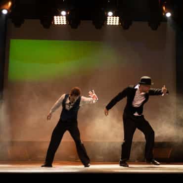 Zwei Männer tanzen auf einer Bühne.
