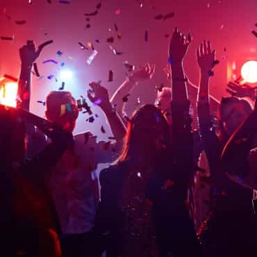 Menschen feiern auf einer Party im roten Scheinwerferlicht.