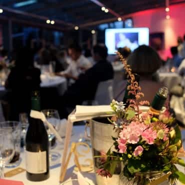 Ein mit Blumen dekorierter Tisch bei einer Gala Veranstaltung.