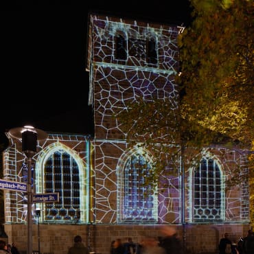 Mittels Architekturbeleuchtung und Videomapping inszenierte Kirche bei Nacht.